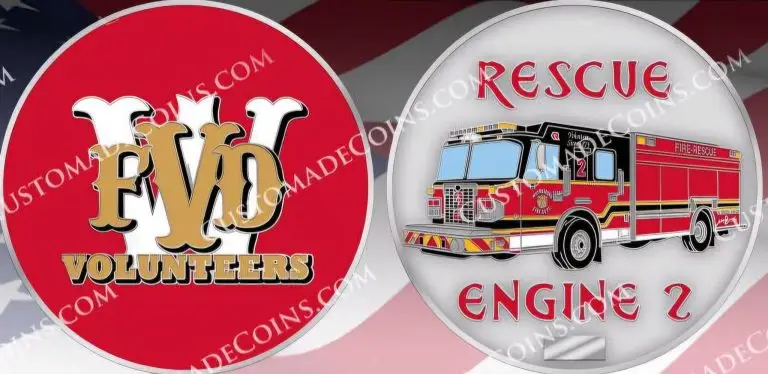 A two-sided coin features on one side a red background with a gold and white "FVD Volunteers" emblem. The other side shows a fire engine with the text "Rescue Engine 2" in red on a silver background. The "V" in “Volunteers” is overlapped by "F" and "D" respectively.